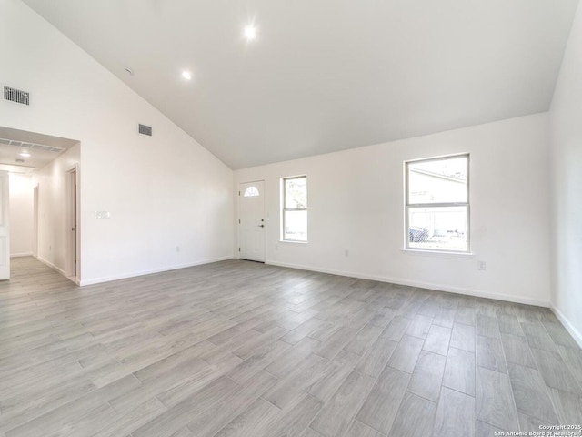 unfurnished room with high vaulted ceiling and light wood-type flooring