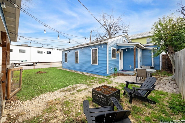 rear view of house with an outdoor fire pit and a yard