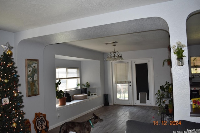 foyer entrance with hardwood / wood-style flooring, an inviting chandelier, and a textured ceiling