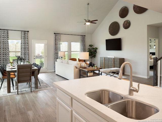 kitchen featuring sink, white cabinetry, high vaulted ceiling, light hardwood / wood-style flooring, and ceiling fan