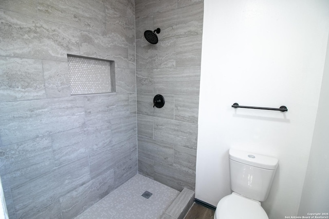 bathroom featuring a tile shower and toilet