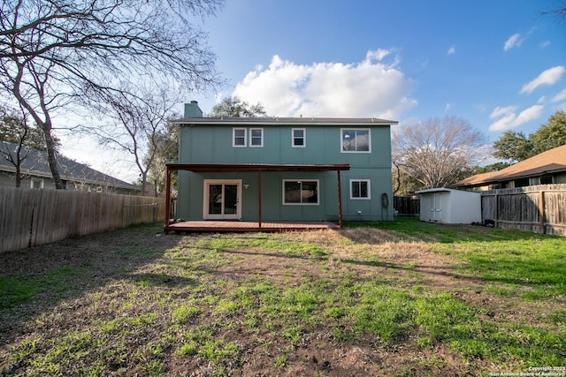 back of property featuring a wooden deck, a storage unit, and a yard