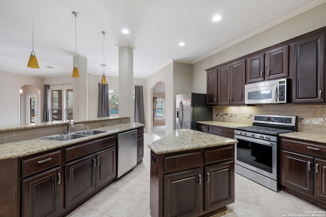 kitchen featuring sink, appliances with stainless steel finishes, hanging light fixtures, a center island, and dark brown cabinetry