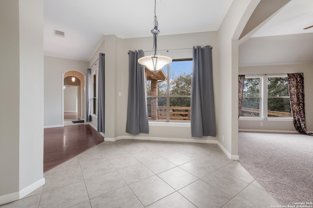 unfurnished dining area with crown molding and light tile patterned floors