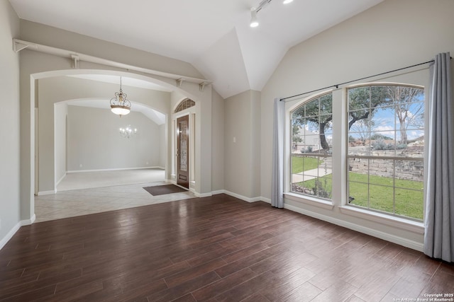 interior space with a notable chandelier, vaulted ceiling, hardwood / wood-style floors, and rail lighting