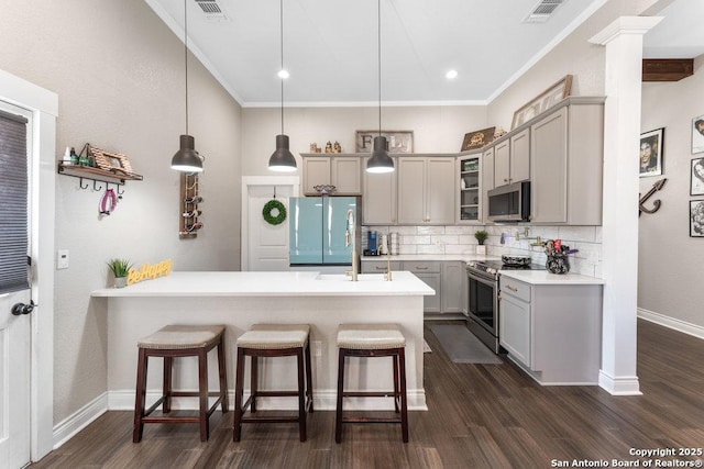 kitchen featuring pendant lighting, stainless steel appliances, gray cabinets, and decorative backsplash