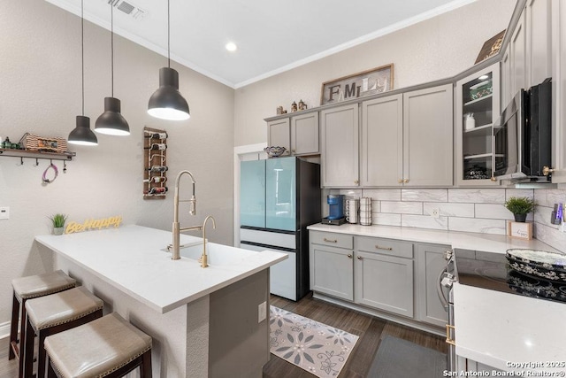 kitchen with dark wood-type flooring, a breakfast bar, crown molding, decorative light fixtures, and appliances with stainless steel finishes