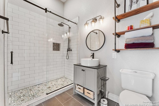 bathroom with tile patterned flooring, vanity, a shower with shower door, and toilet