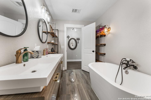 bathroom with hardwood / wood-style flooring, vanity, and a tub to relax in