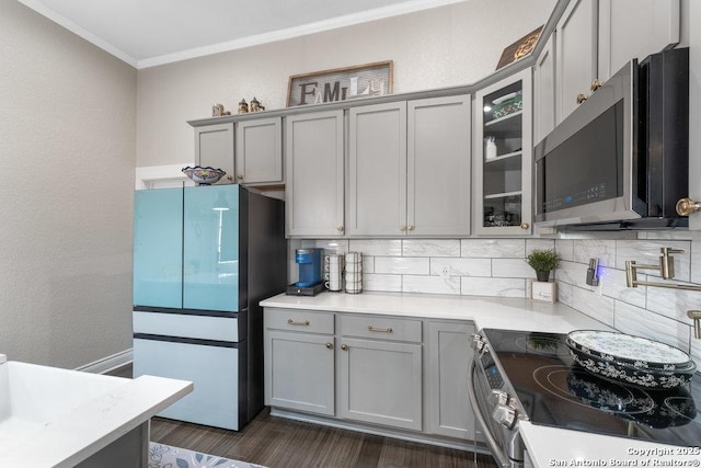 kitchen with dark wood-type flooring, ornamental molding, appliances with stainless steel finishes, gray cabinets, and backsplash