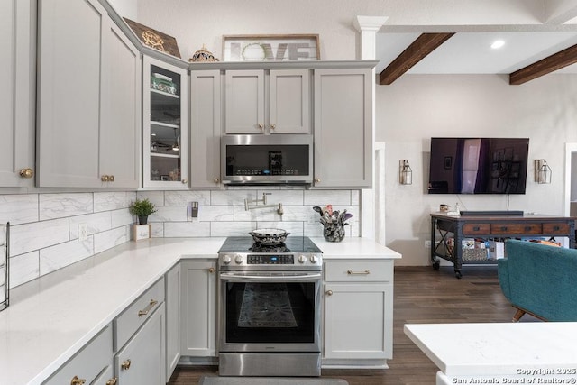 kitchen featuring stainless steel appliances, gray cabinets, beam ceiling, and decorative backsplash