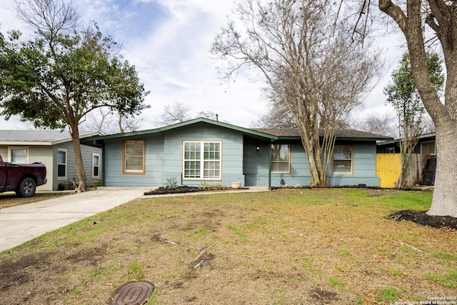 single story home featuring a front yard, concrete driveway, fence, and brick siding