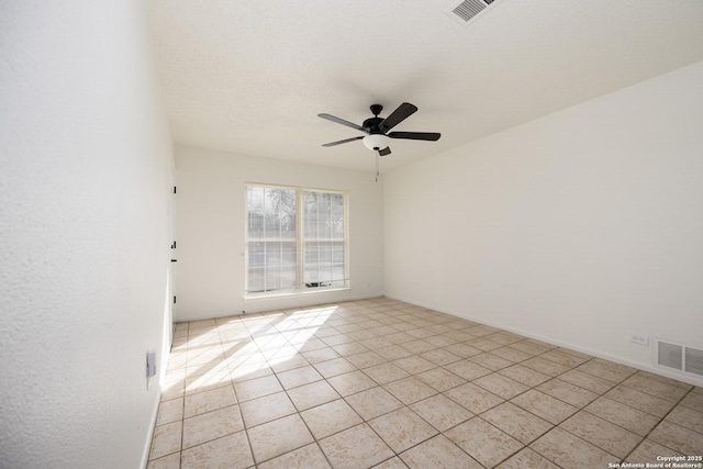 spare room with a textured ceiling, light tile patterned floors, visible vents, and ceiling fan