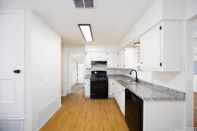 kitchen with black appliances, white cabinets, visible vents, and a sink