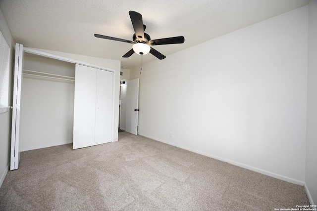 unfurnished bedroom featuring baseboards, carpet, a closet, a textured ceiling, and a ceiling fan