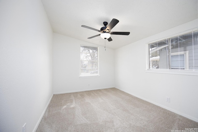 carpeted empty room with vaulted ceiling, a ceiling fan, and baseboards