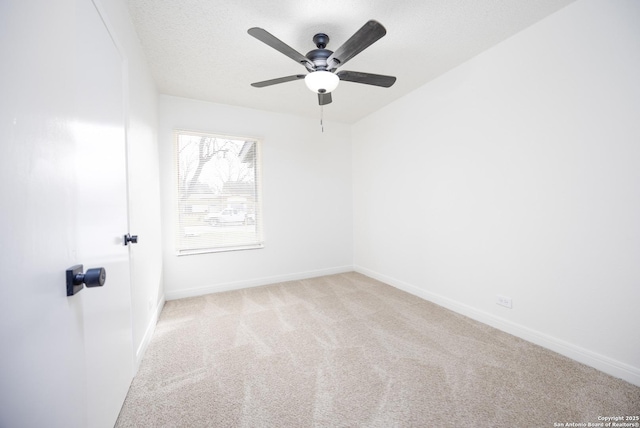 carpeted spare room featuring a textured ceiling, baseboards, and a ceiling fan