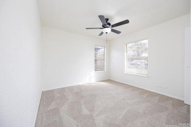 carpeted spare room featuring baseboards and ceiling fan