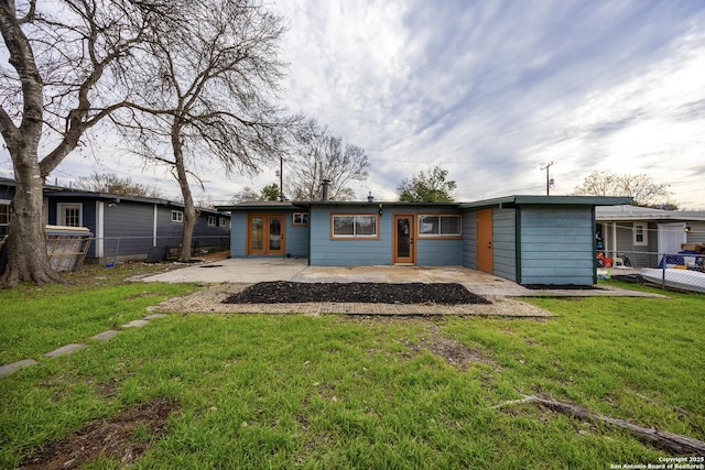 rear view of house with a patio area, a lawn, fence, and french doors