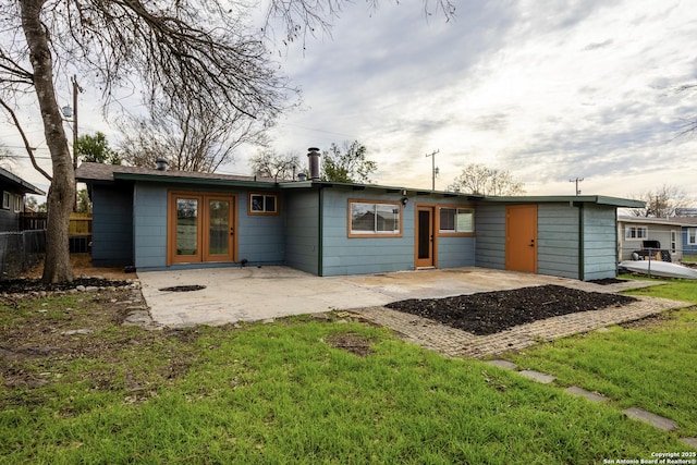 rear view of property with a lawn, french doors, a patio, and fence