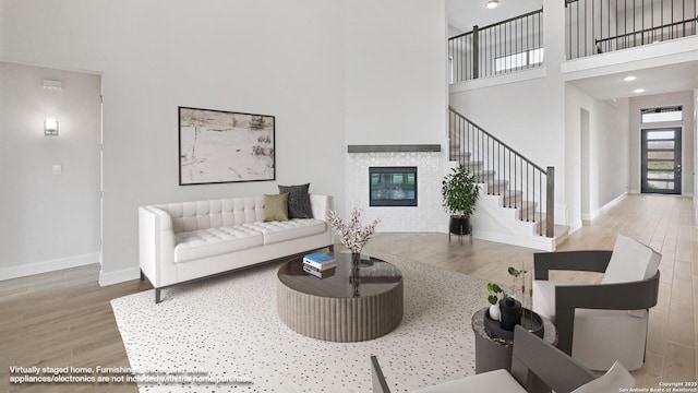 305 Hulda Trl, New Braunfels, TX 78130 - living room with wood finished floors, a high ceiling, stairway, baseboards, and a glass covered fireplace
