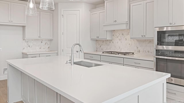 305 Hulda Trl, New Braunfels, TX 78130 - kitchen with a sink, stainless steel gas cooktop, decorative backsplash, light countertops, and an island with sink