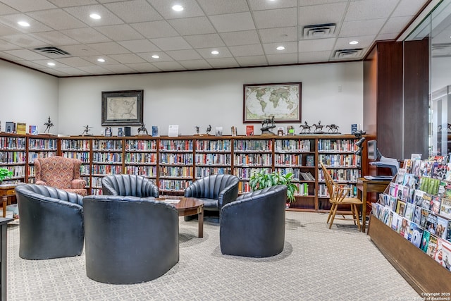 living area featuring carpet and a drop ceiling