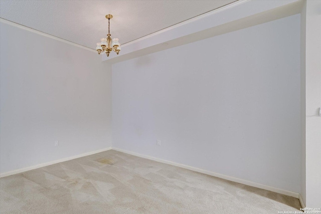 carpeted spare room with an inviting chandelier