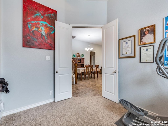 hallway featuring an inviting chandelier and carpet flooring