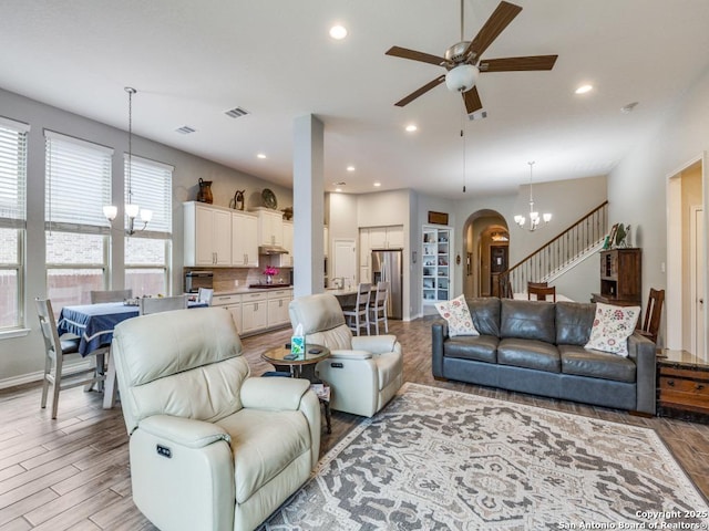 living room featuring ceiling fan with notable chandelier and light wood-type flooring