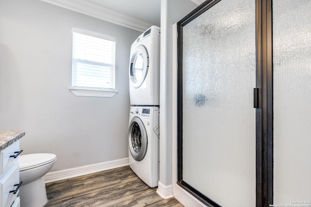 laundry area with dark wood-type flooring, stacked washer and dryer, and ornamental molding