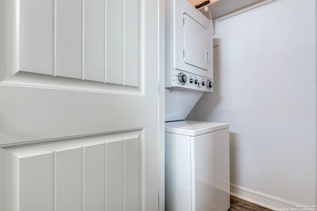 washroom with stacked washer / drying machine and dark hardwood / wood-style flooring