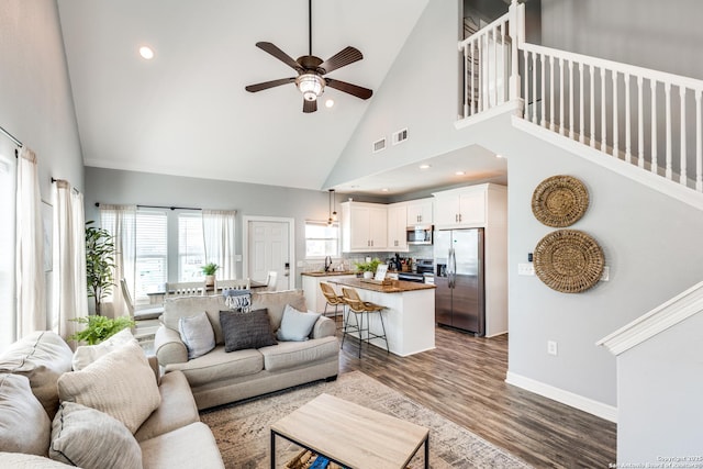 living room featuring hardwood / wood-style flooring, ceiling fan, and high vaulted ceiling