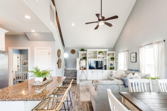 kitchen featuring a breakfast bar, ceiling fan, white cabinetry, light stone counters, and dark hardwood / wood-style flooring