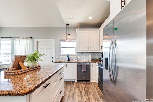 kitchen with decorative light fixtures, sink, dark stone countertops, white cabinets, and stainless steel appliances