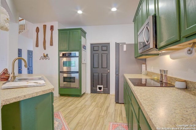 kitchen featuring appliances with stainless steel finishes, sink, light hardwood / wood-style floors, and green cabinetry