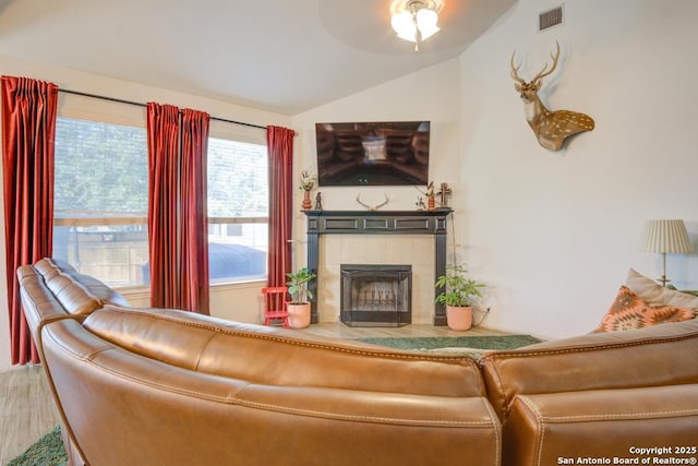 living room featuring ceiling fan, lofted ceiling, wood-type flooring, and a tile fireplace