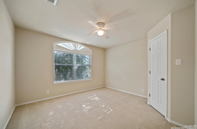 empty room featuring ceiling fan and light colored carpet