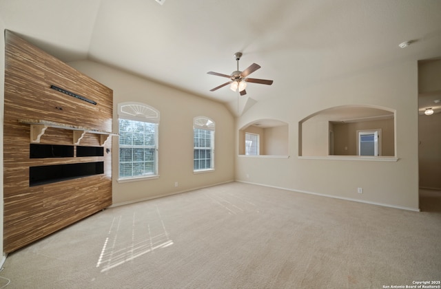 unfurnished living room featuring ceiling fan, a healthy amount of sunlight, lofted ceiling, and light carpet