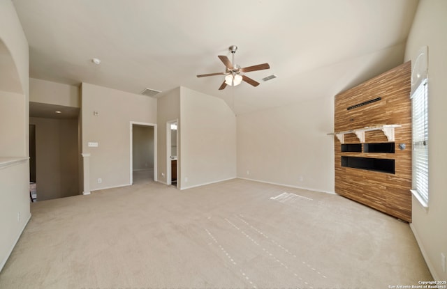 unfurnished living room featuring a fireplace, vaulted ceiling, light colored carpet, and ceiling fan