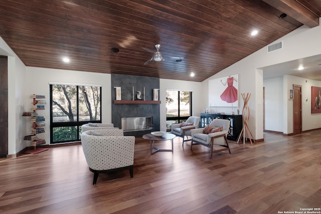 living room featuring a tile fireplace, vaulted ceiling, a healthy amount of sunlight, and wood ceiling