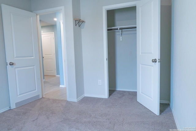 unfurnished bedroom with light carpet and a closet