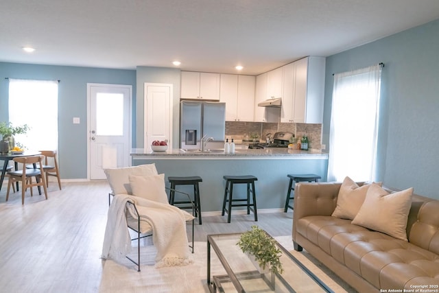 living room with a healthy amount of sunlight, sink, and light hardwood / wood-style floors