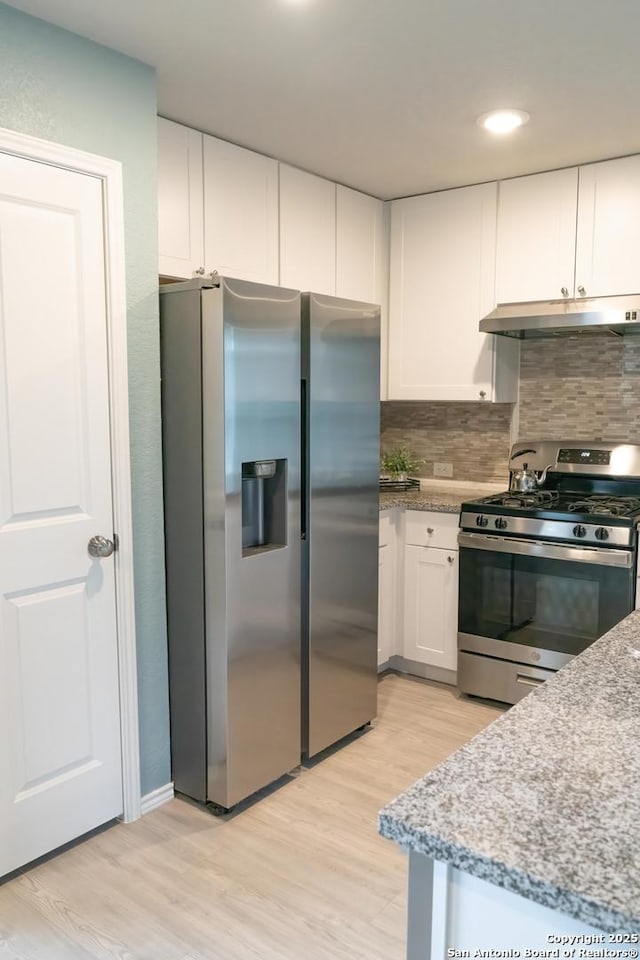 kitchen featuring light stone countertops, white cabinetry, appliances with stainless steel finishes, and light hardwood / wood-style flooring