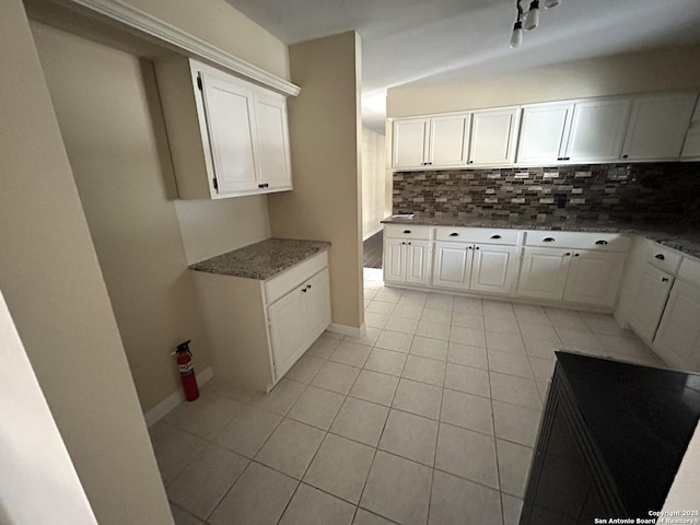 kitchen with tasteful backsplash, white cabinetry, and light tile patterned flooring