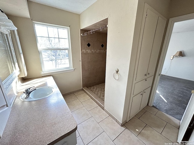 bathroom featuring a tile shower, vanity, tile patterned flooring, and a textured ceiling