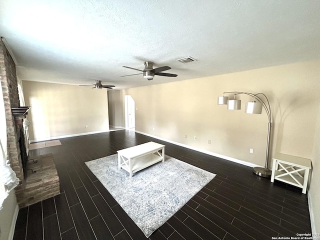 unfurnished living room with ceiling fan, a textured ceiling, and a fireplace