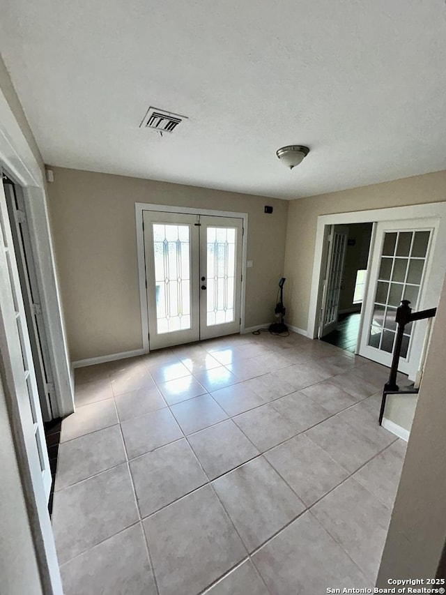 empty room featuring french doors and light tile patterned floors