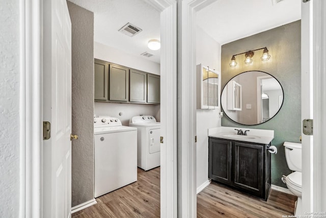 washroom with cabinets, sink, light hardwood / wood-style flooring, and washer and dryer