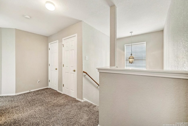 hall featuring carpet flooring and a textured ceiling